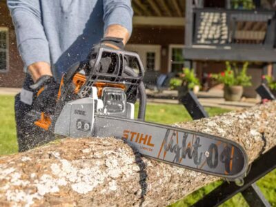 Man using a STIHL chainsaw to cut through a log outdoors, demonstrating professional power and reliability of STIHL equipment sold at  in Lindale, Texas